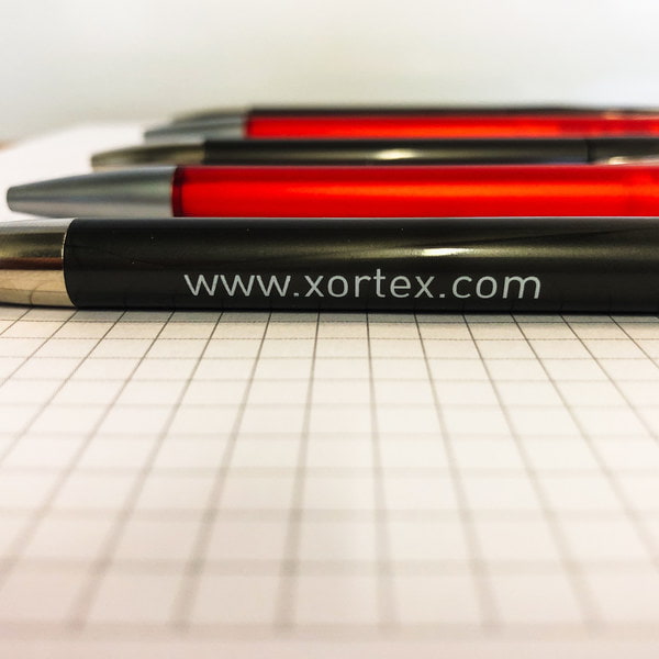 Kugelschreiber der Webagentur XORTEX in rot und grau auf kariertem Block