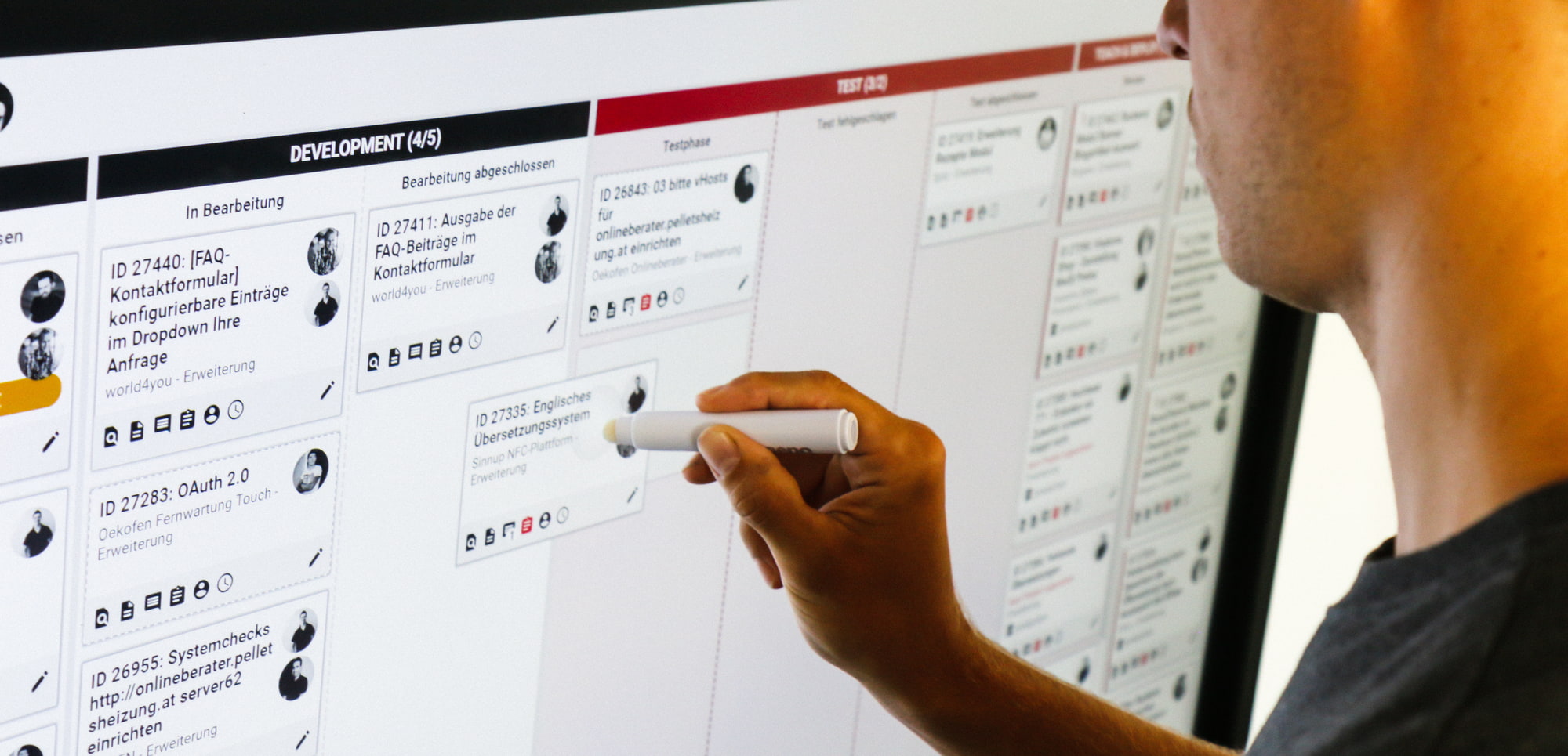 Mitarbeiter steht beim Touchscreen mit geöffnetem, digitalen XORTEX Kanban-Board