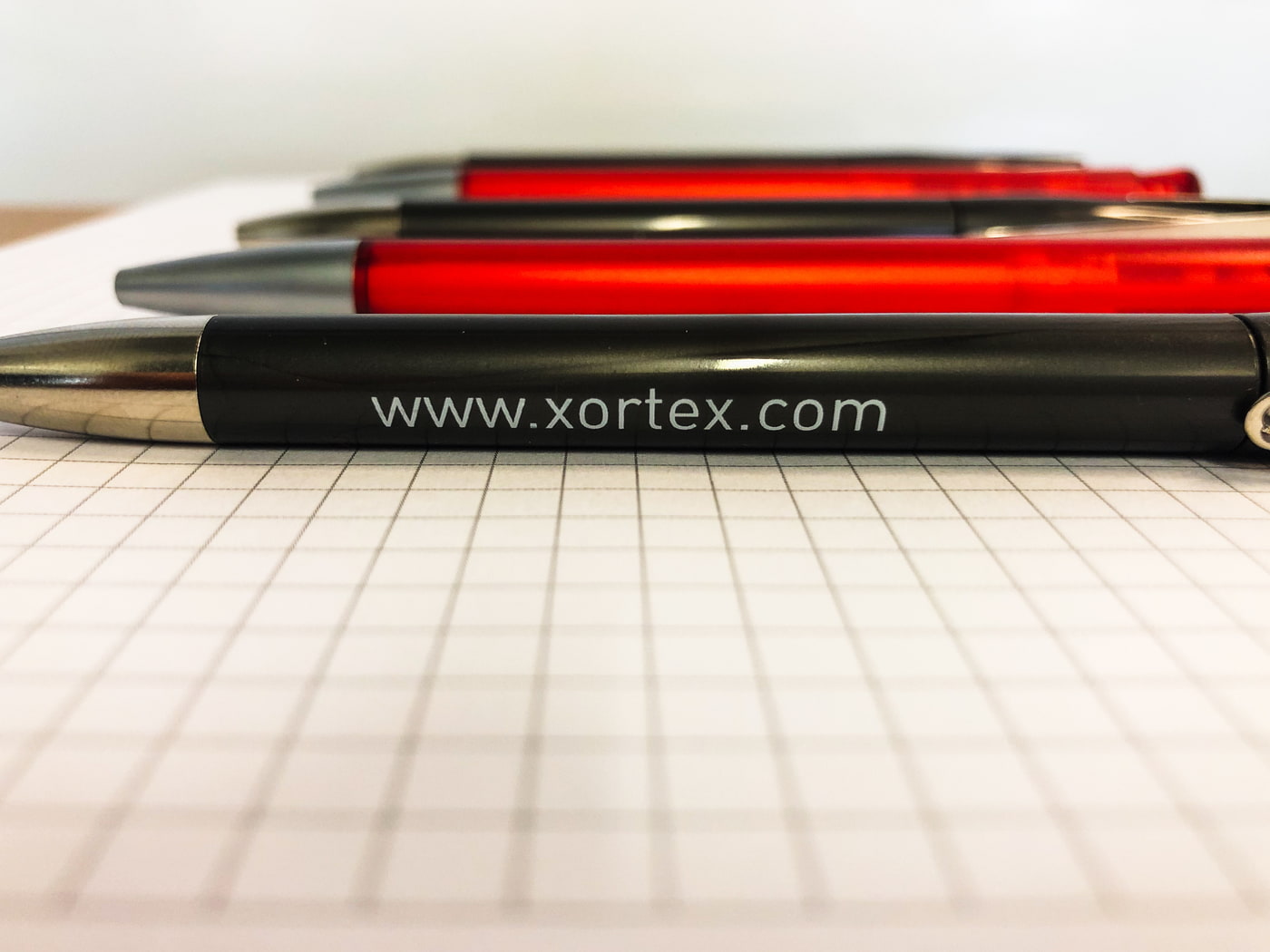 Kugelschreiber der Webagentur XORTEX in rot und grau auf kariertem Block