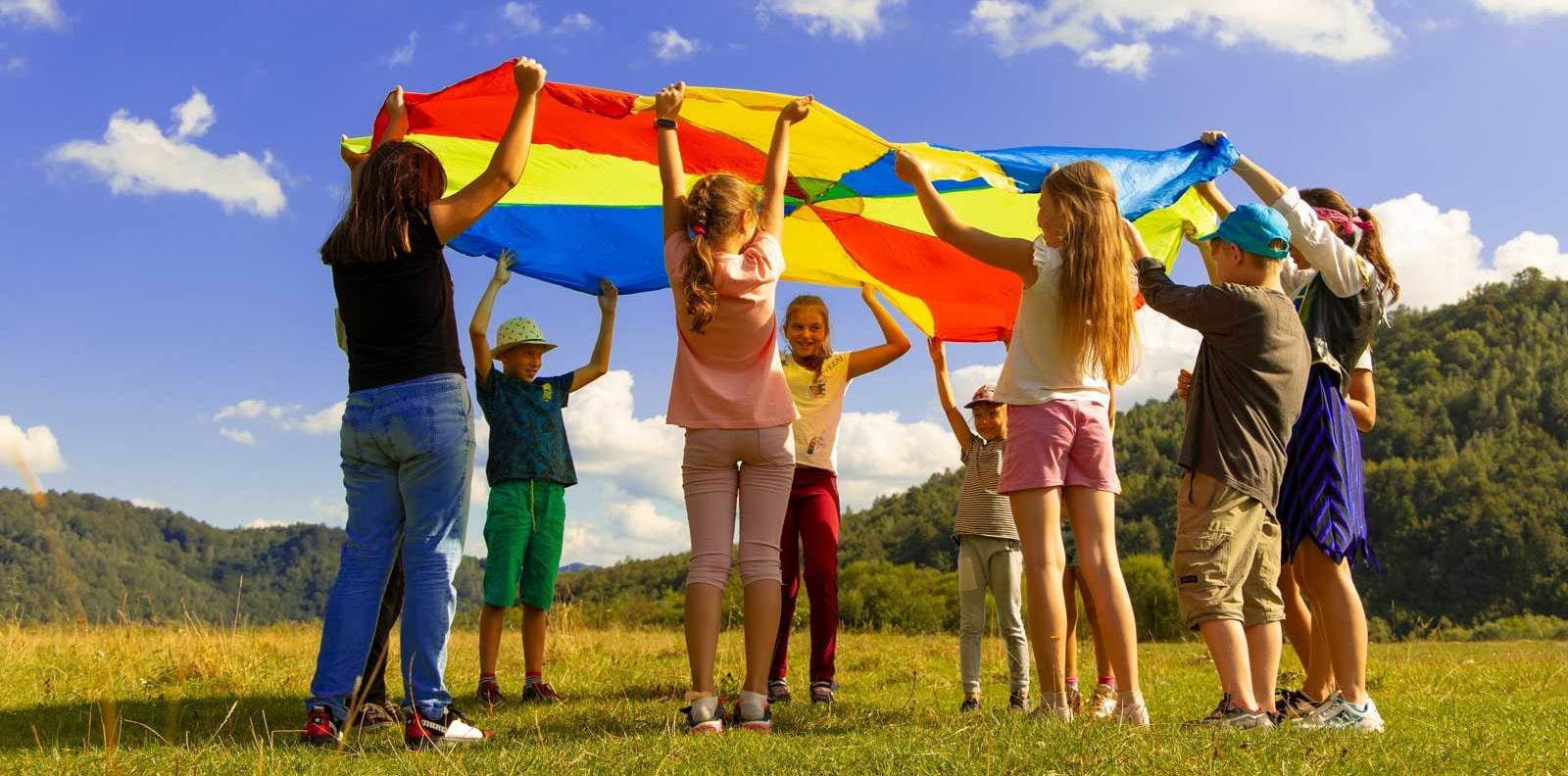 Eine Gruppe von Kindern spielt mit einem Regenbogentuch